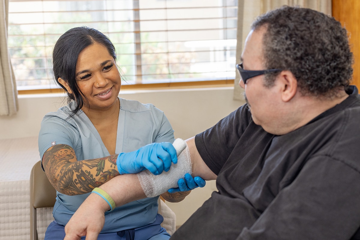 A caregiver with a male resident needing complex wound care at the Sunrise Post Acute facility